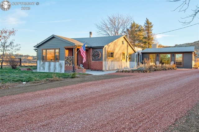 view of front of house featuring brick siding, fence, and a chimney