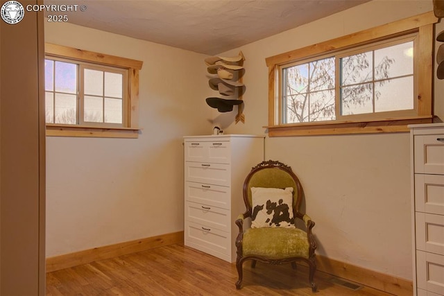 living area featuring baseboards, plenty of natural light, visible vents, and light wood-style floors