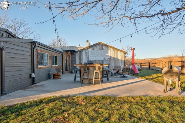 back of property featuring a patio area, fence, outdoor dry bar, and a lawn