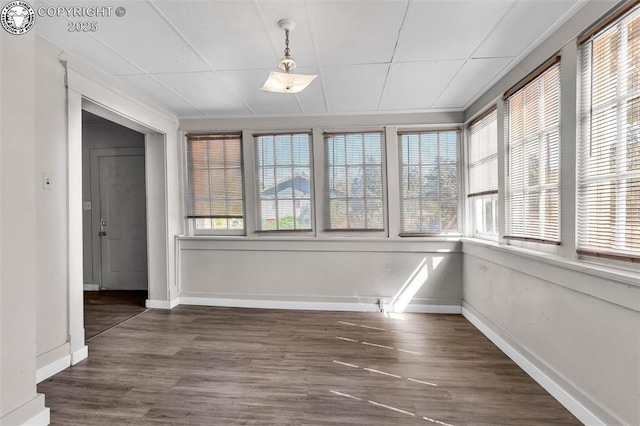unfurnished sunroom featuring a wealth of natural light, wood finished floors, and baseboards