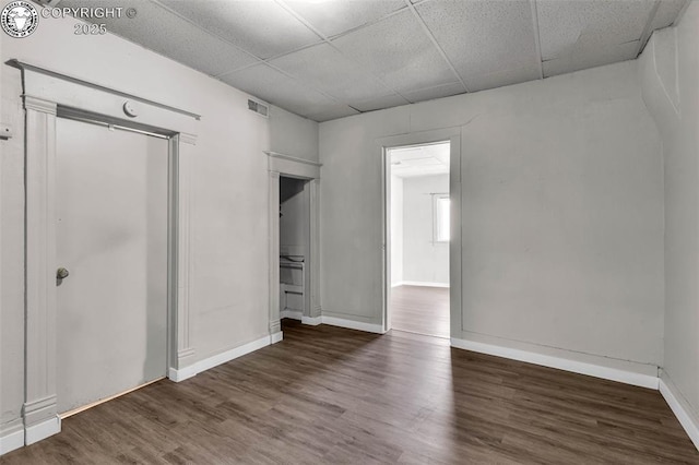 unfurnished bedroom with visible vents, baseboards, a paneled ceiling, and wood finished floors