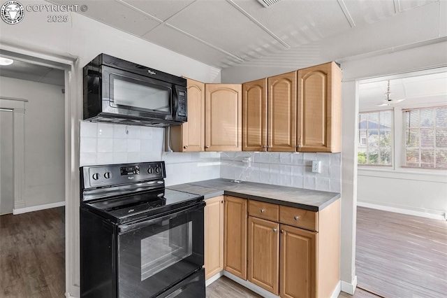 kitchen with light wood-style floors, decorative backsplash, baseboards, and black appliances