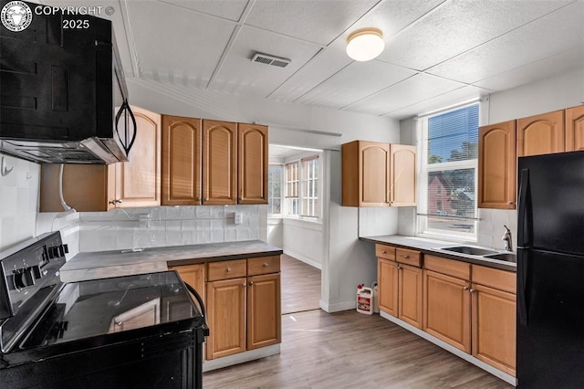 kitchen with backsplash, black appliances, visible vents, light wood finished floors, and a sink