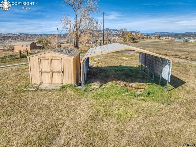 view of outbuilding featuring a carport, a mountain view, and a lawn