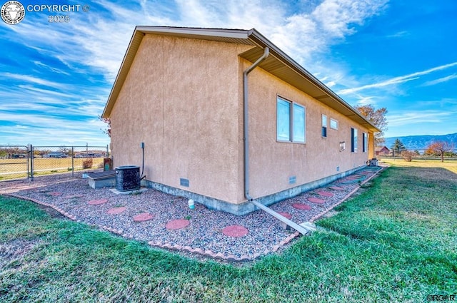 view of side of home featuring a yard and central AC unit