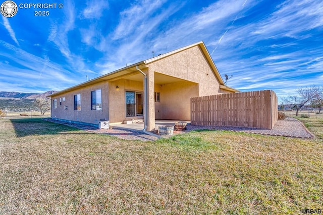 back of property with a mountain view, a lawn, and a patio