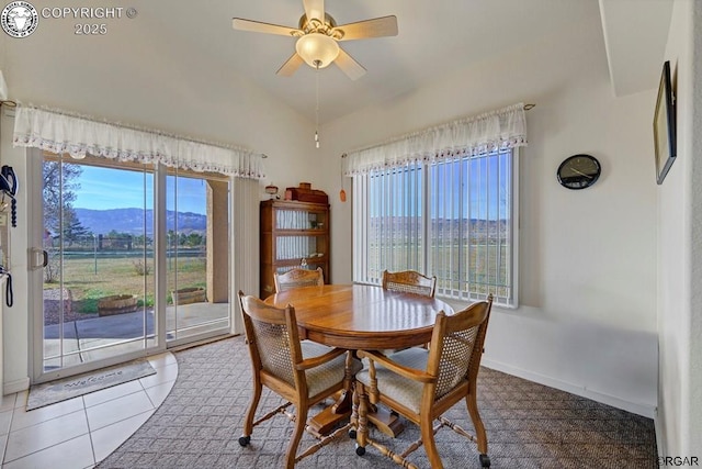 tiled dining area with ceiling fan, a healthy amount of sunlight, a mountain view, and vaulted ceiling