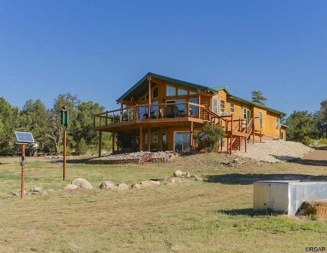 rear view of property with a wooden deck and a lawn