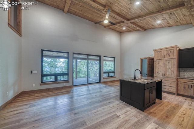 79 Terrazo Abajo, Westcliffe, CO 81252 - kitchen with a wood ceiling with exposed beams, light wood finished floors, open floor plan, light stone counters, and a high ceiling