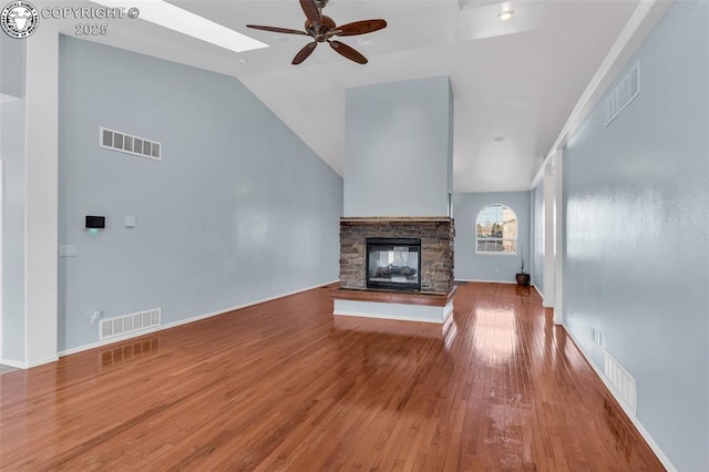 unfurnished living room featuring ceiling fan, visible vents, a fireplace, and wood finished floors