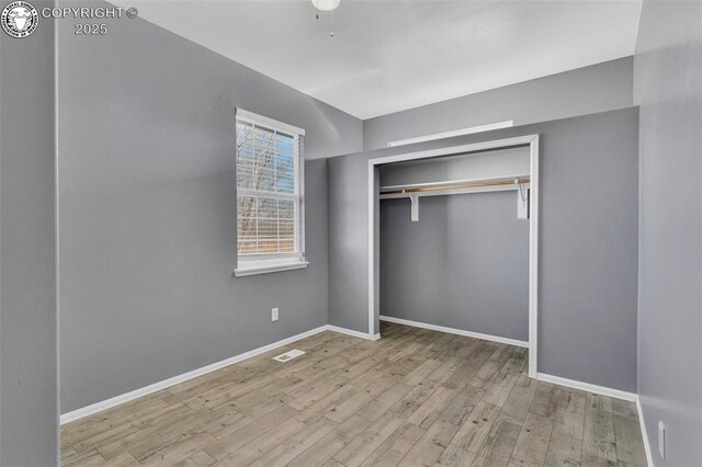 unfurnished bedroom with light wood-style flooring, a closet, visible vents, and baseboards