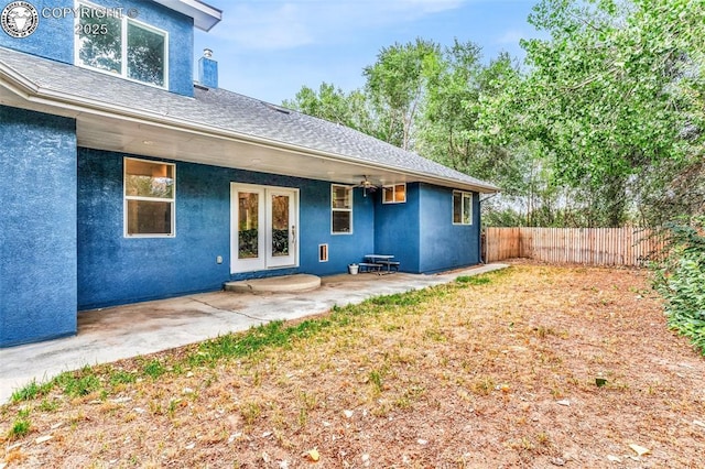 back of property with roof with shingles, stucco siding, fence, and a patio