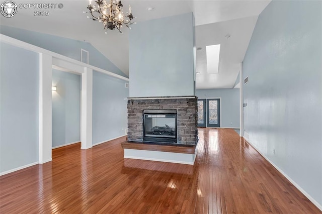 unfurnished living room featuring lofted ceiling, a fireplace, wood finished floors, and baseboards