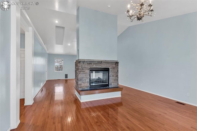 unfurnished living room with baseboards, visible vents, wood finished floors, vaulted ceiling, and a fireplace