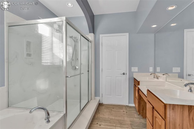 full bathroom featuring a stall shower, double vanity, a sink, and wood finished floors