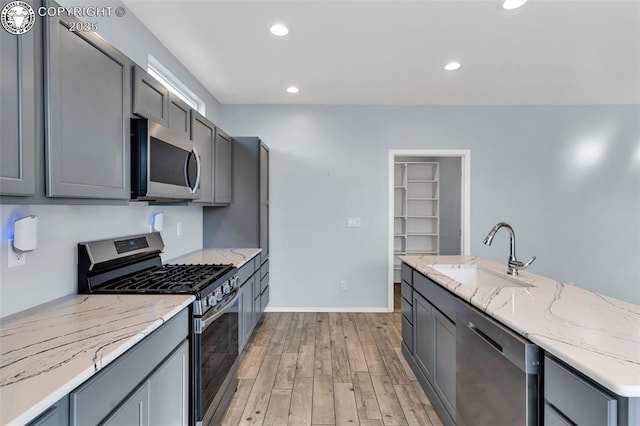 kitchen featuring stainless steel appliances, a sink, and gray cabinetry