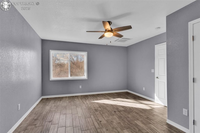 spare room with ceiling fan, wood finished floors, visible vents, and baseboards