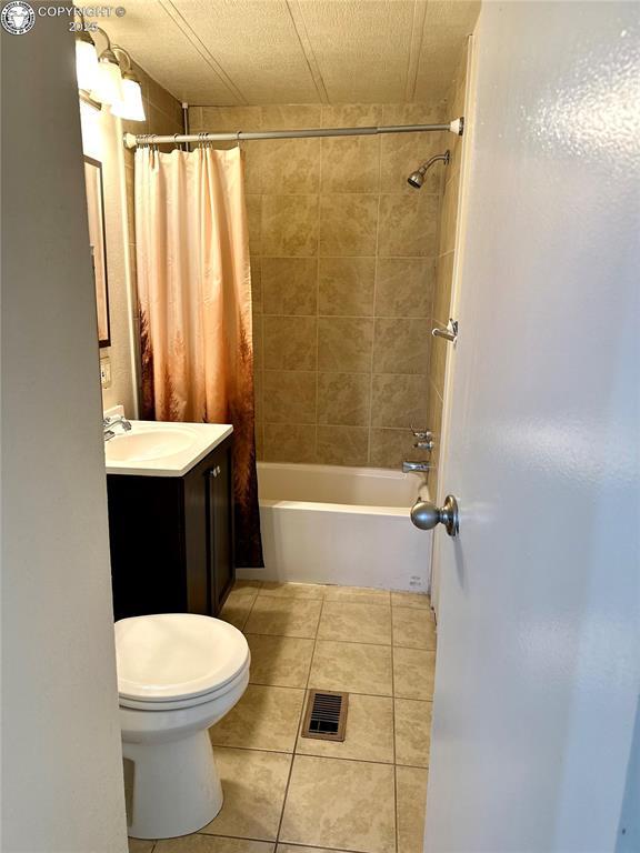 bathroom with vanity, toilet, visible vents, tile patterned flooring, and shower / bath combination with curtain