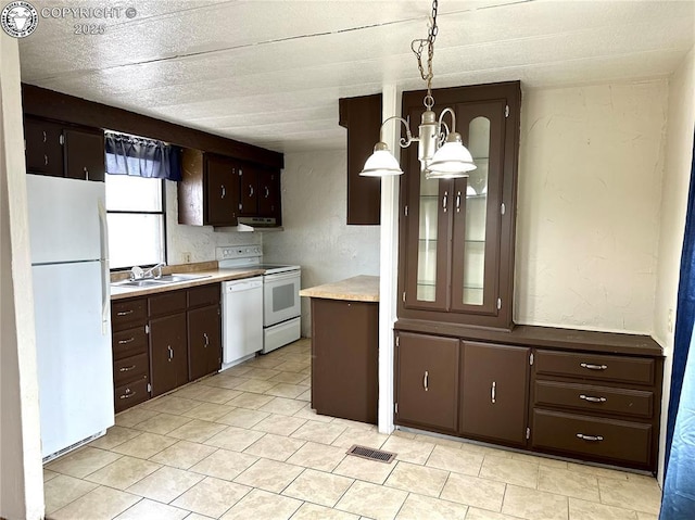 kitchen featuring light countertops, white appliances, dark brown cabinetry, and a sink