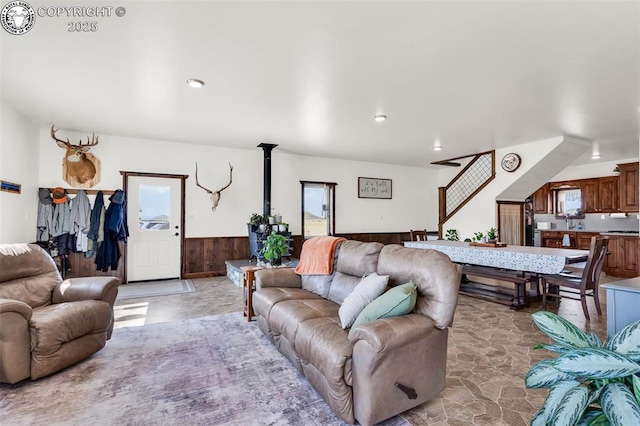 3491 County Road 215th Rd, Westcliffe, CO 81252 - living area featuring healthy amount of natural light, a wainscoted wall, a wood stove, wooden walls, and light stone finish floors