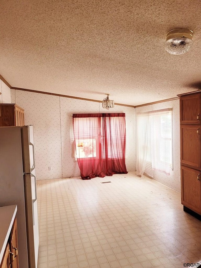 interior space with crown molding, a textured ceiling, and white fridge