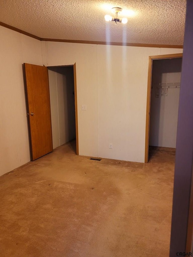 carpeted spare room with ornamental molding and a textured ceiling