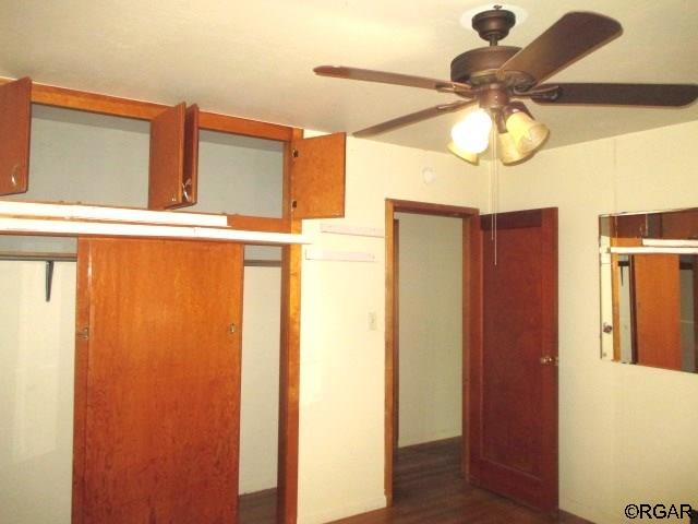 unfurnished bedroom featuring dark wood-type flooring and ceiling fan