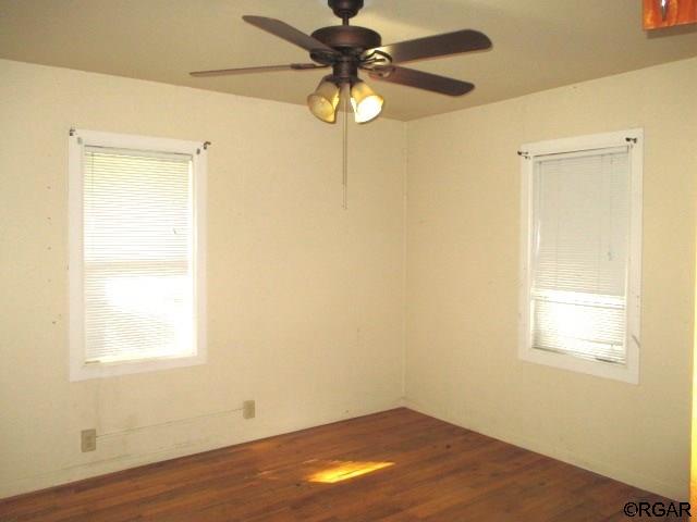 unfurnished room with ceiling fan and dark hardwood / wood-style floors