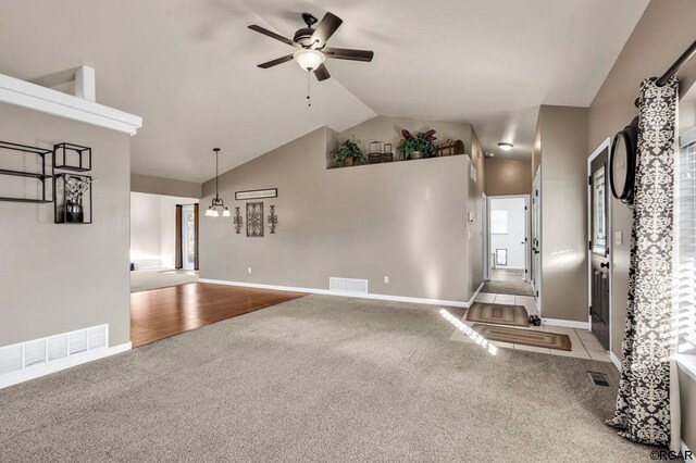 unfurnished living room with vaulted ceiling, light carpet, and ceiling fan