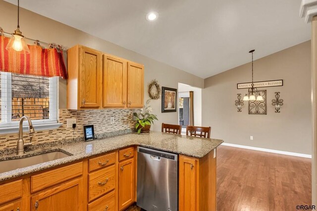 kitchen with sink, decorative light fixtures, stainless steel dishwasher, kitchen peninsula, and light wood-type flooring