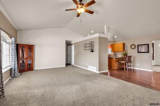 unfurnished living room with dark colored carpet, lofted ceiling, and ceiling fan