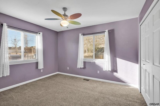 carpeted spare room with ceiling fan