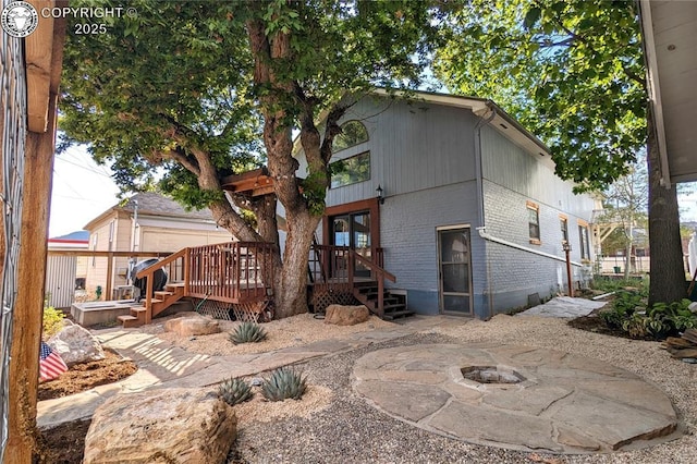 back of house with a wooden deck and an outdoor fire pit