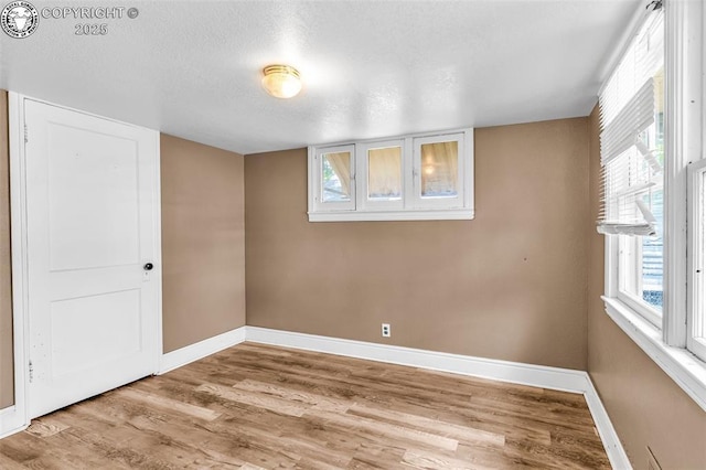 basement with baseboards, wood finished floors, a textured ceiling, and plenty of natural light