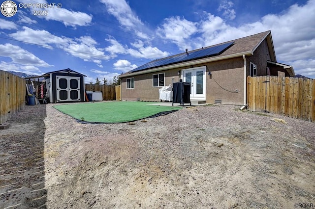 rear view of house featuring a fenced backyard, an outdoor structure, french doors, crawl space, and a storage shed