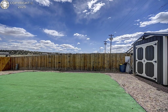 view of yard featuring an outdoor structure, a fenced backyard, and a shed