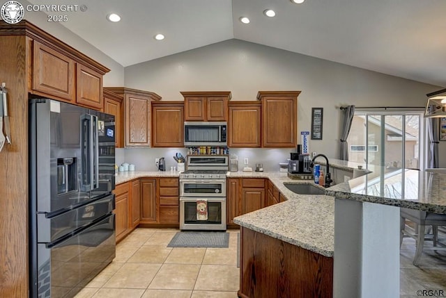 kitchen with light tile patterned floors, brown cabinetry, a peninsula, a sink, and stainless steel appliances