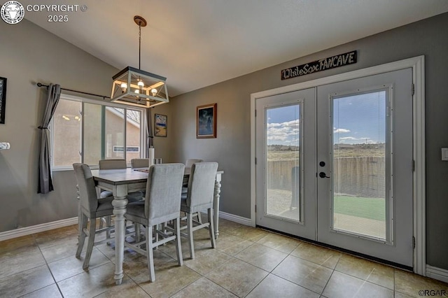 dining space with light tile patterned floors, baseboards, lofted ceiling, french doors, and a notable chandelier