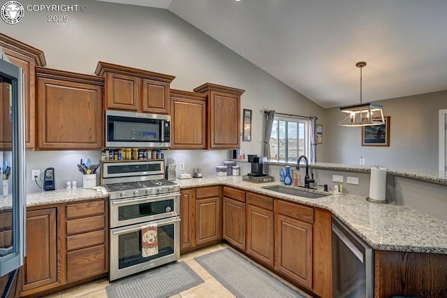 kitchen featuring a sink, brown cabinets, appliances with stainless steel finishes, and a peninsula