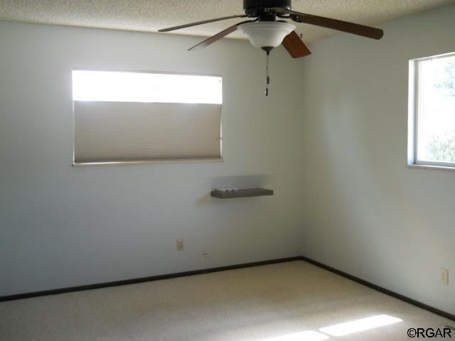 carpeted spare room featuring a textured ceiling and ceiling fan