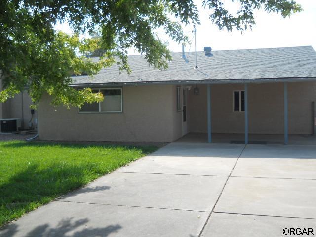 rear view of house with a carport, a yard, and central air condition unit