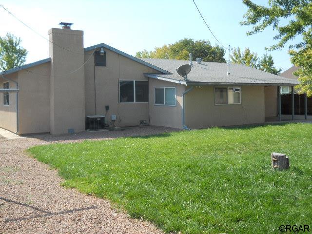 back of property with a yard and central air condition unit