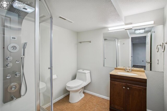 bathroom featuring vanity, a textured ceiling, a shower with shower door, and toilet