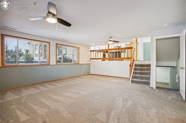 unfurnished living room with ceiling fan, carpet floors, and a textured ceiling