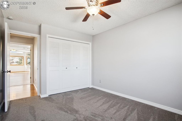 unfurnished bedroom featuring dark carpet, a textured ceiling, a closet, and ceiling fan