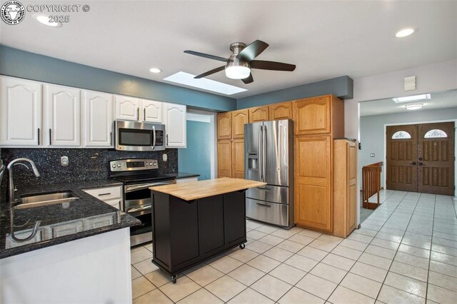 kitchen with sink, stainless steel appliances, a center island, tasteful backsplash, and dark stone counters