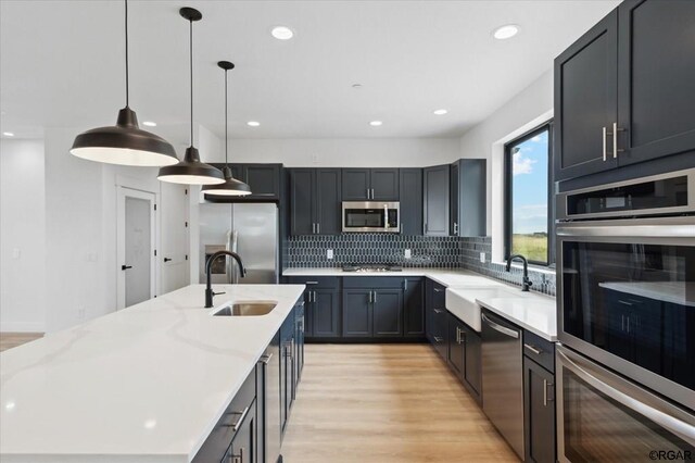 kitchen featuring tasteful backsplash, appliances with stainless steel finishes, sink, and hanging light fixtures