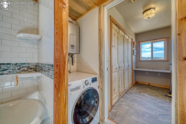 820 Little Horn Dr, Westcliffe, CO 81252 - clothes washing area with baseboards, water heater, stone finish floor, laundry area, and washer / dryer