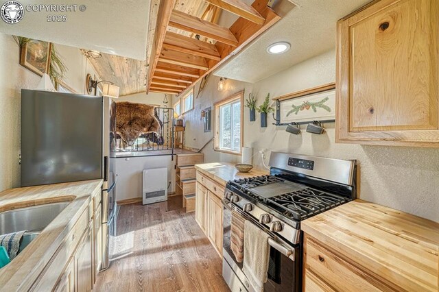 820 Little Horn Dr, Westcliffe, CO 81252 - kitchen with light brown cabinetry, vaulted ceiling, light wood-type flooring, wood counters, and appliances with stainless steel finishes