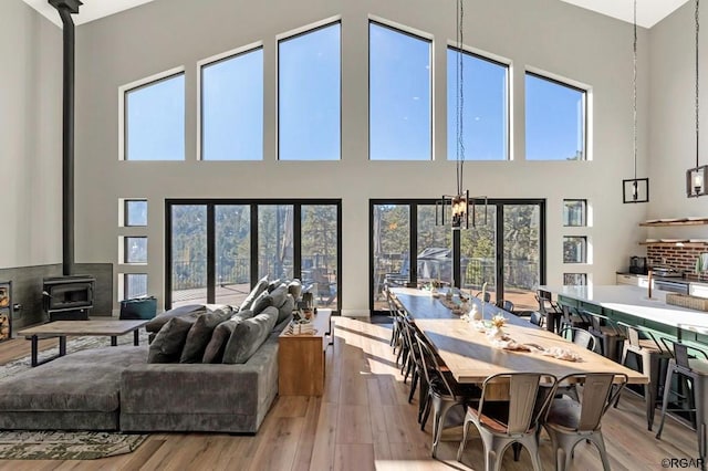 living room with a towering ceiling, light wood-type flooring, and a wood stove